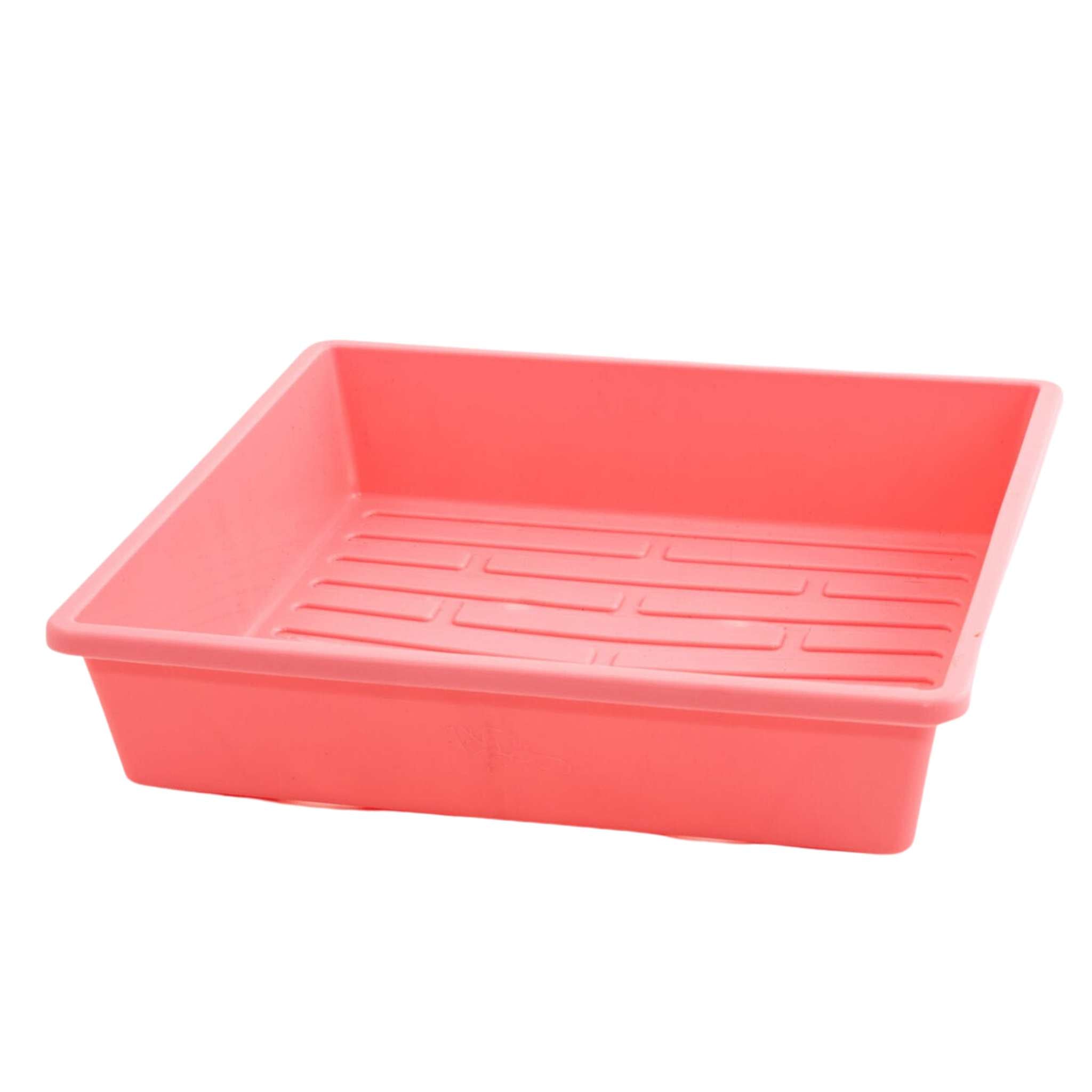 Coral-colored plastic tray with drainage holes on a white background