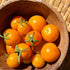 Wooden bowl filled with California Sungold tomatoes on a woven surface