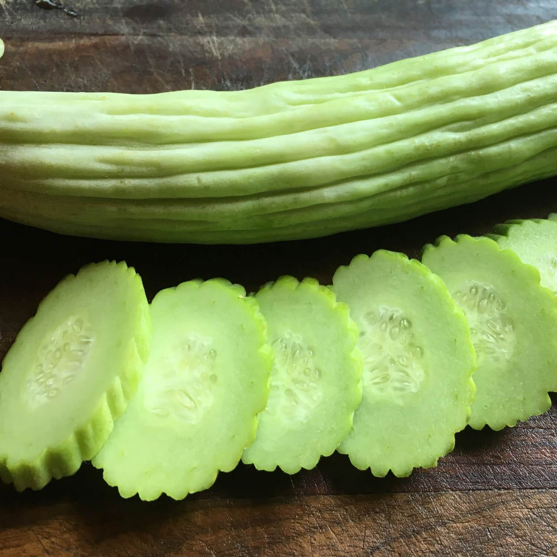 Whole and sliced Armenian cucumber on a wooden surface