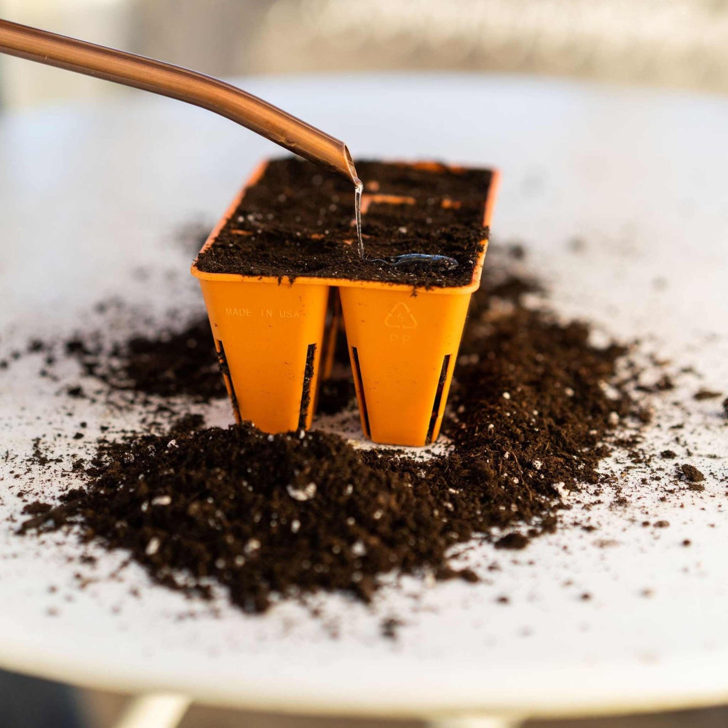 Orange seedling tray with soil being filled in a close-up shot. 