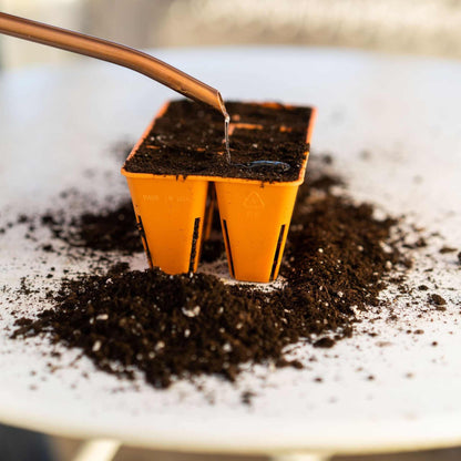 Orange seedling tray with soil being filled in a close-up shot. 
